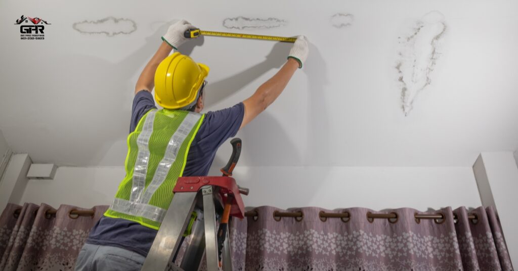 Worried homeowner looking up at a leaking ceiling during a storm