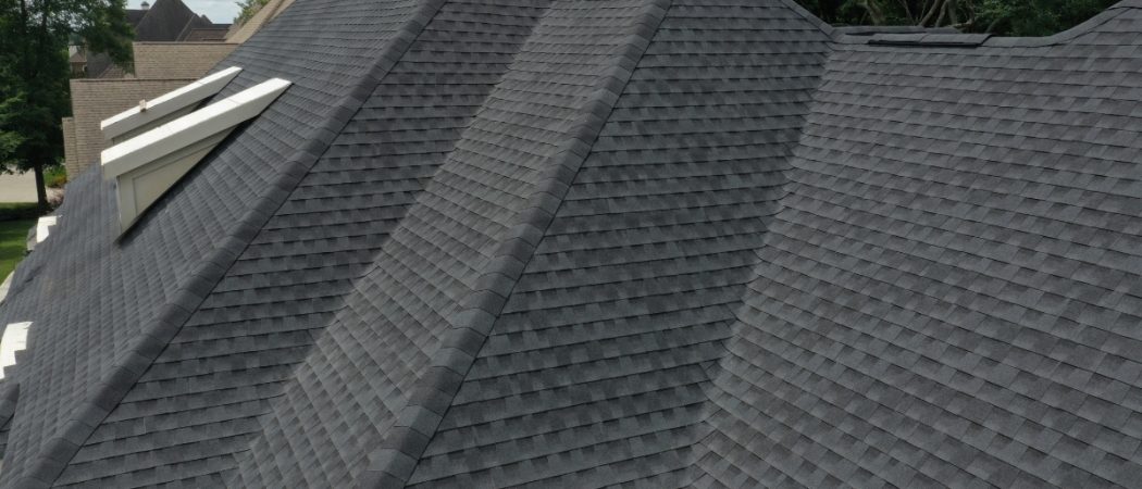 Professional roofer installing shingles on a residential roof with Utah mountain backdrop