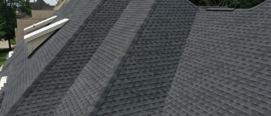 Professional roofer installing shingles on a residential roof with Utah mountain backdrop