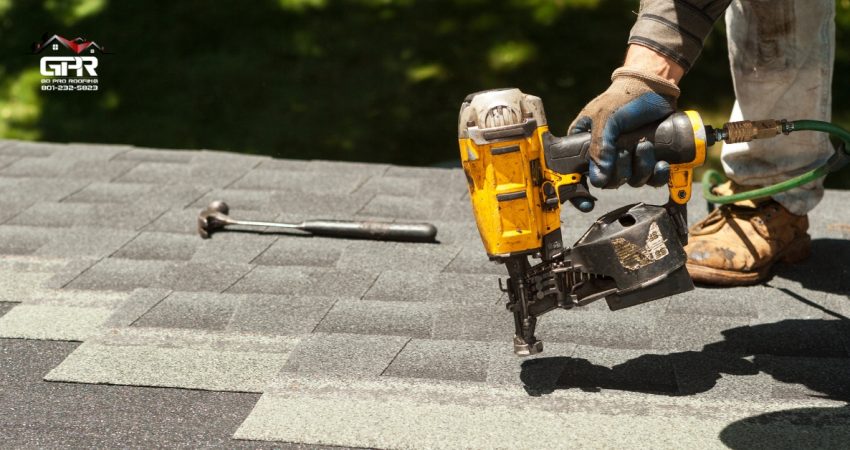 Roofing contractor replacing damaged asphalt shingles on a suburban home roof.
