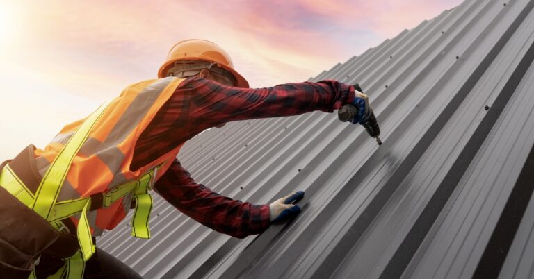 Professional roofer installing metal roofing panels on a residential home in Utah