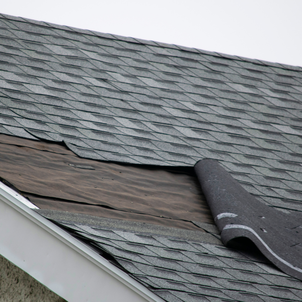 Close-up of cracked shingles and flashing on damaged roof