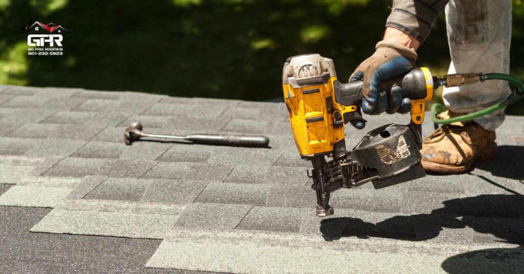 Roofing contractor replacing damaged asphalt shingles on a suburban home roof.